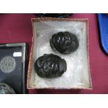 A Pair of Black Lacquered Ethnic Heads, one with its eyes shut and the other with its eyes open, 7