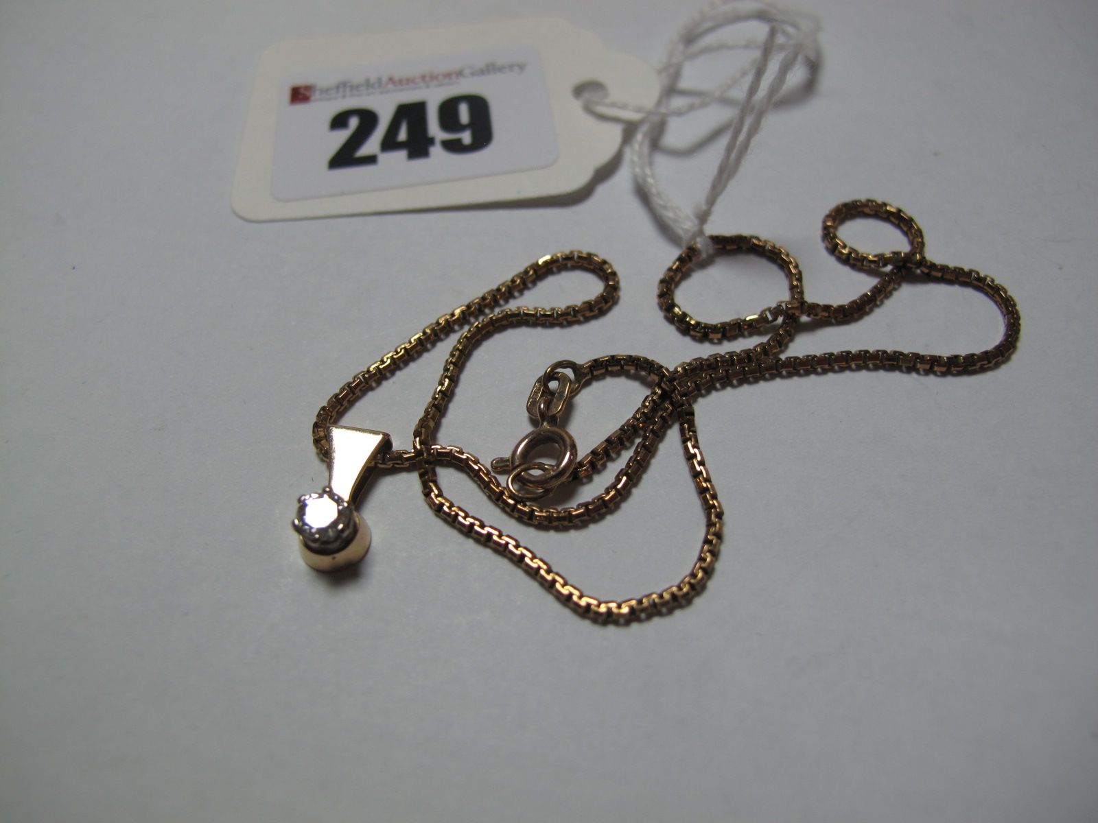 A Single Stone Diamond Pendant, claw set, on 9ct gold chain.