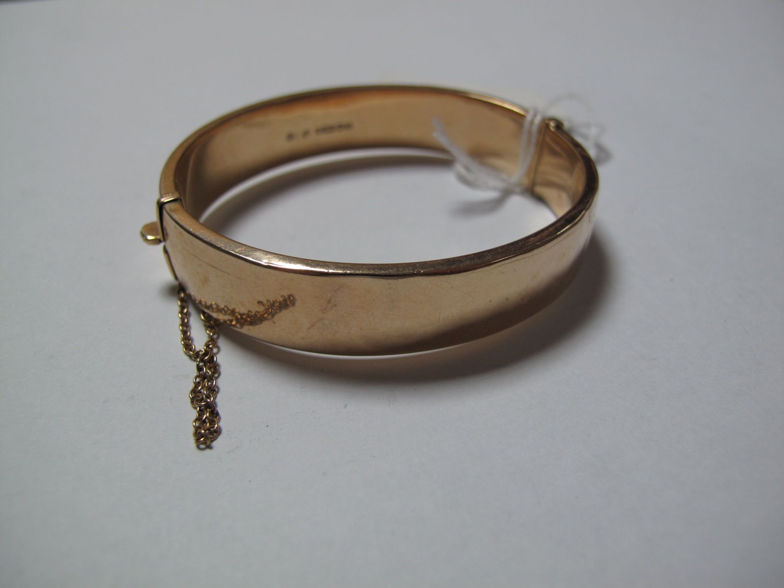 A 9ct Gold Bangle, leaf scroll engraved to the front, hinged to snap clasp.