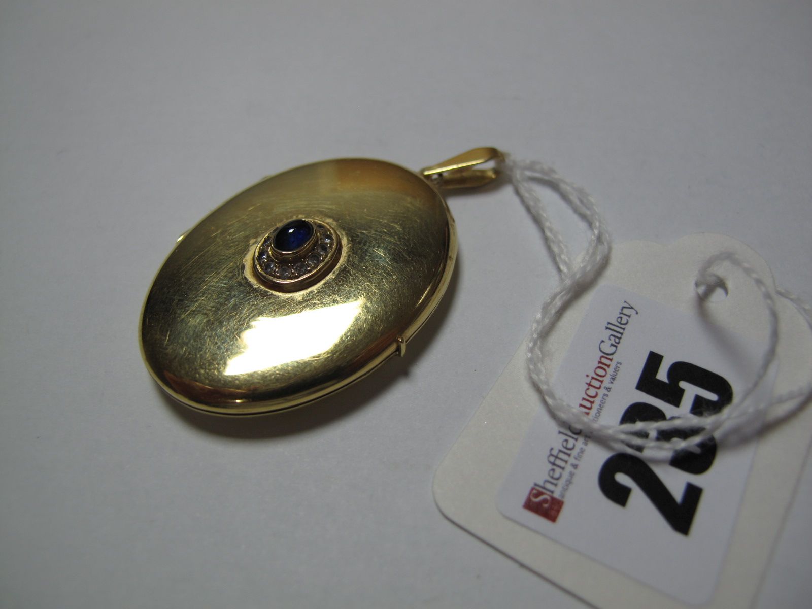 An Oval Locket Pendant, oval cabochon set to the centre, on long bale, stamped "750".