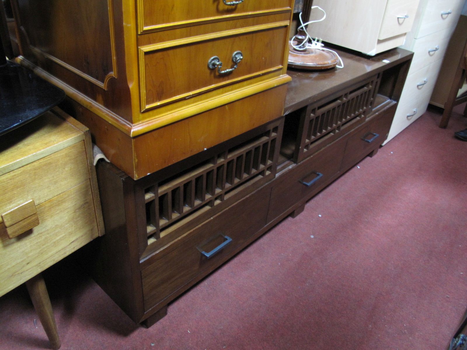 A Modern Hardwood TV Stand, having pierced sliding shelves over three short drawers, on block