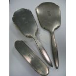 A Hallmarked Silver Three Piece Dressing Table Set, comprising hand mirror and two brushes, each