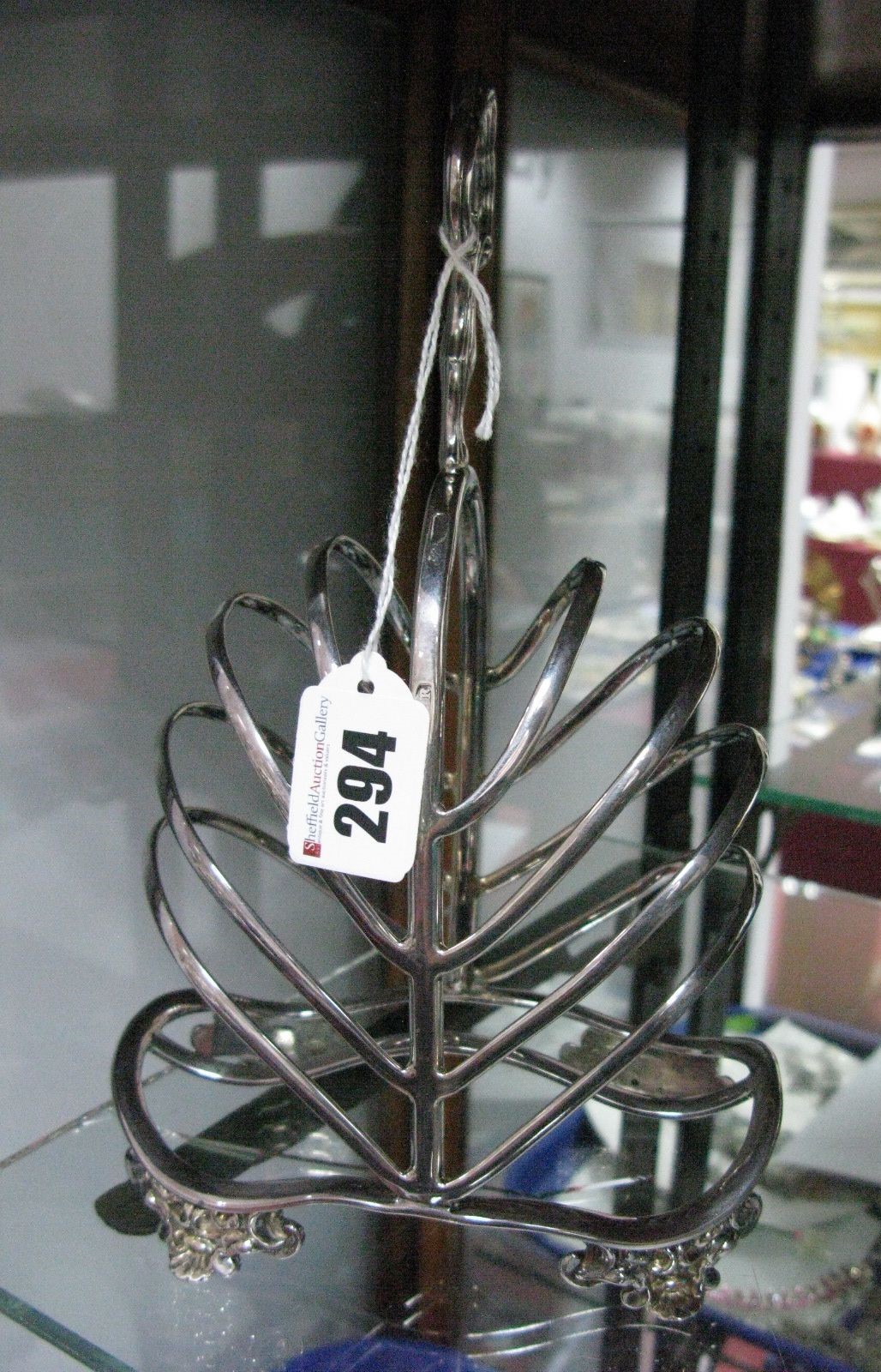 A Martin Hall & Co Plated Toast Rack, with eight bars and high central loop handle, raised on four