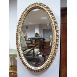 An Oval bevelled Mirror, in cream painted, pierced wooden frame. Another similar. (2)