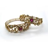 A Pair of Middle Eastern Ruby and Diamond Set Bangles, each central flowerhead claw set with