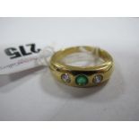 An 18ct Gold Emerald and Diamond Set Ring, rubover set to the centre with a circular emerald,