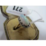 An Opal and Diamond Cluster Ring, the central high oval cabochon opal claw set, within border of