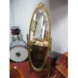 A XX Century Gilded Cheval Mirror, an oval shaped mirror with ribbon decoration, on swept feet,