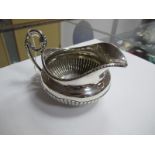 A Hallmarked Silver Jug, (marks indistinct) of compressed semi reeded form, with scroll loop