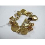 A Belcher Link Charm Bracelet, stamped "750", suspending numerous novelty charm pendants,