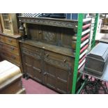 An Oak Court Cupboard, having cup and cover supports to upper section, over panelled doors on turned