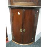 An Early XIX Century Mahogany Bow Fronted Corner Cupboard, with a stepped cornice above cupboards,