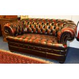 A good quality ox blood red leather two seater Chesterfield sofa, raised on bun feet,