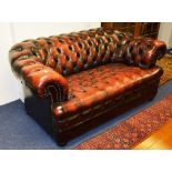 A good quality ox blood red leather two seater Chesterfield sofa, raised on bun feet,