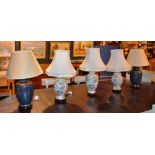 Two pairs of ceramic table lamps, with shades, on blue and white grounds, converted to electricity,