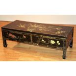 A modern Japanned coffee table, with two drawers decorated with foliate panels on black ground,