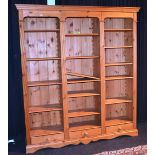 A modern pine three section open bookcase, each section terminating with single drawer,