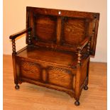 An early 20th century oak monks bench, the adjustable top raised above hinged box seat,