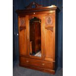 A late 19th/early 20th century mahogany wardrobe, the carved pediment raised above mirrored door,