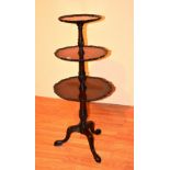 An Edwardian mahogany dumb waiter, with pie crust decoration, raised on turned columns,