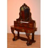 A Victorian mahogany dressing table, the swing mirror raised above small drawers,