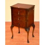 A Queen Anne style walnut bedside cabinet, with three drawers,