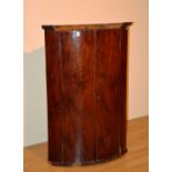 A George III mahogany bow front corner cupboard, with two panelled doors,