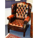 A good quality ox blood leather wing Chesterfield armchair, raised on block supports,
