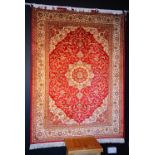 A Kashan silk rug, the central cream foliate medallion on red ground,