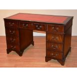 A reproduction kneehole desk, with red tooled leather inset to top, above three drawers,