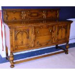 A Jacobean style oak sideboard, with carved pediment above two drawers, flanked by a panelled door,