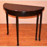 A mahogany demi-lune fold over card table, raised on tapering supports,