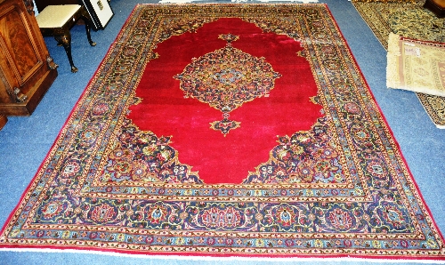 A Persian mashad carpet, with central floral medallion on red ground,