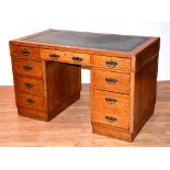 An oak kneehole desk, with leather skiver to top above fitted drawers,