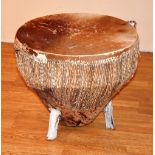 An African animal skin drum, raised on supports,