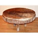 An African animal skin drum/table, raised on supports,