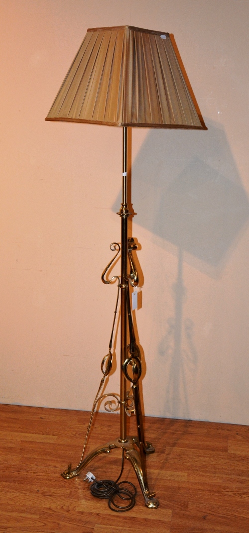 An Art nouveau brass adjustable floor lamp and shade, with stylized decoration,