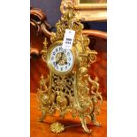 A French brass ornate mantel clock, the cream enamel dial with Arabic numerals,