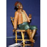 A Blackamoor type glazed pottery figure, in the form of a slave sitting on faux bamboo chair,