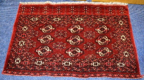 A small persian rug, decorated with rows of geometrical motifs, on red ground,