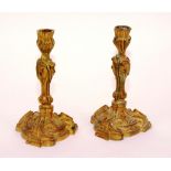 A pair of small French Rococo ormolu candlesticks,