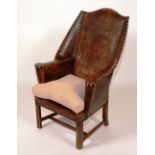 A leather wing armchair, circa 1900, with brass-studded frame,