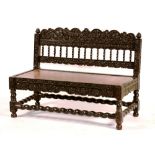 A 17th century style Batavian ebonised banquette, with elaborately carved frame,