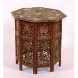 A Burmese carved folding octagonal table, with fretwork panels and carved floral top,