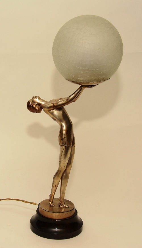 An Art Deco painted bronze figural table lamp, in the form of a nude female holding glass shade,