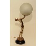 An Art Deco painted bronze figural table lamp, in the form of a nude female holding glass shade,