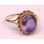 A 9ct gold and amethyst ring, the large central oval cut amethyst within frilly gold bezel setting,