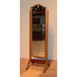 A walnut cheval mirror, raised on scroll supports,