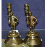 A pair of cast bronze candlesticks in the form of Centurions, raised on circular bases,