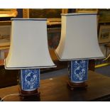 A pair of Oriental blue and white vase lamps, with cream shades,
